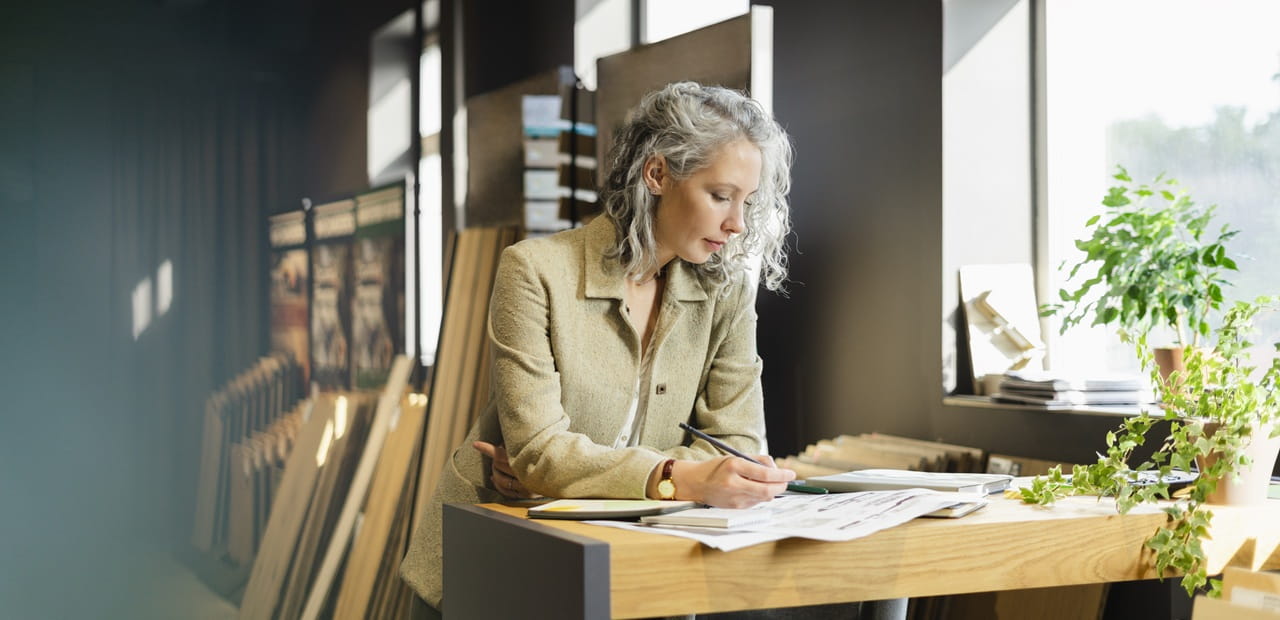 Business owner reviewing plans at a desk, demonstrating sustainable decision-making that can reduce costs and strengthen long-term growth.