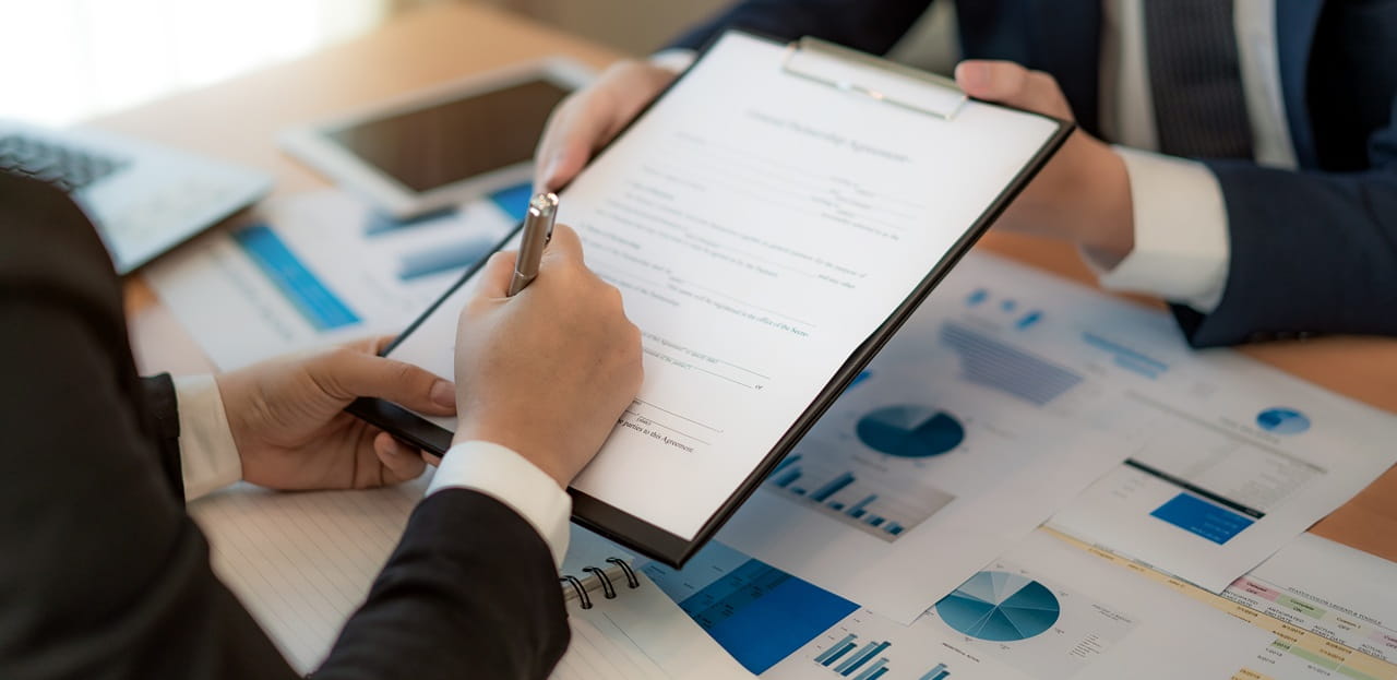 Business owner reviewing insurance documents with an advisor while discussing business liability insurance coverage options.