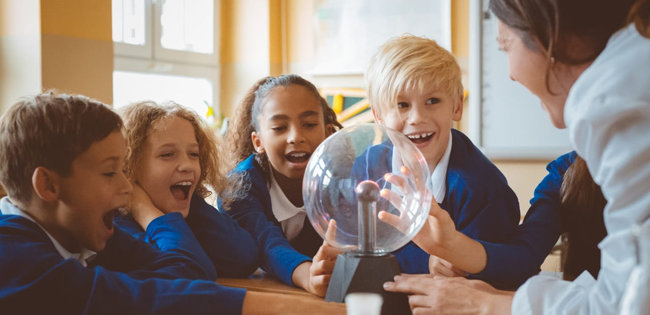 Children participate in a hands-on science lesson with their teacher, highlighting how 529 plan funds can help cover eligible K–12 education expenses.