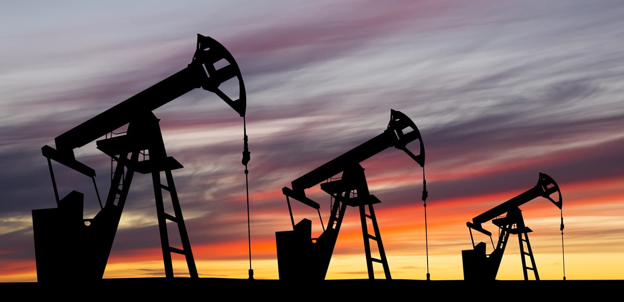 Oil pump jacks silhouetted at sunset, representing oil market volatility as a result of the US-Iran conflict.