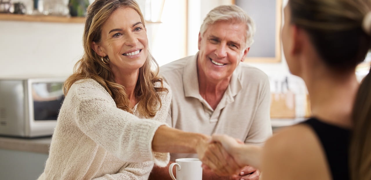 Smiling couple meeting with a financial advisor to discuss secure retirement planning through a trusteed IRA.