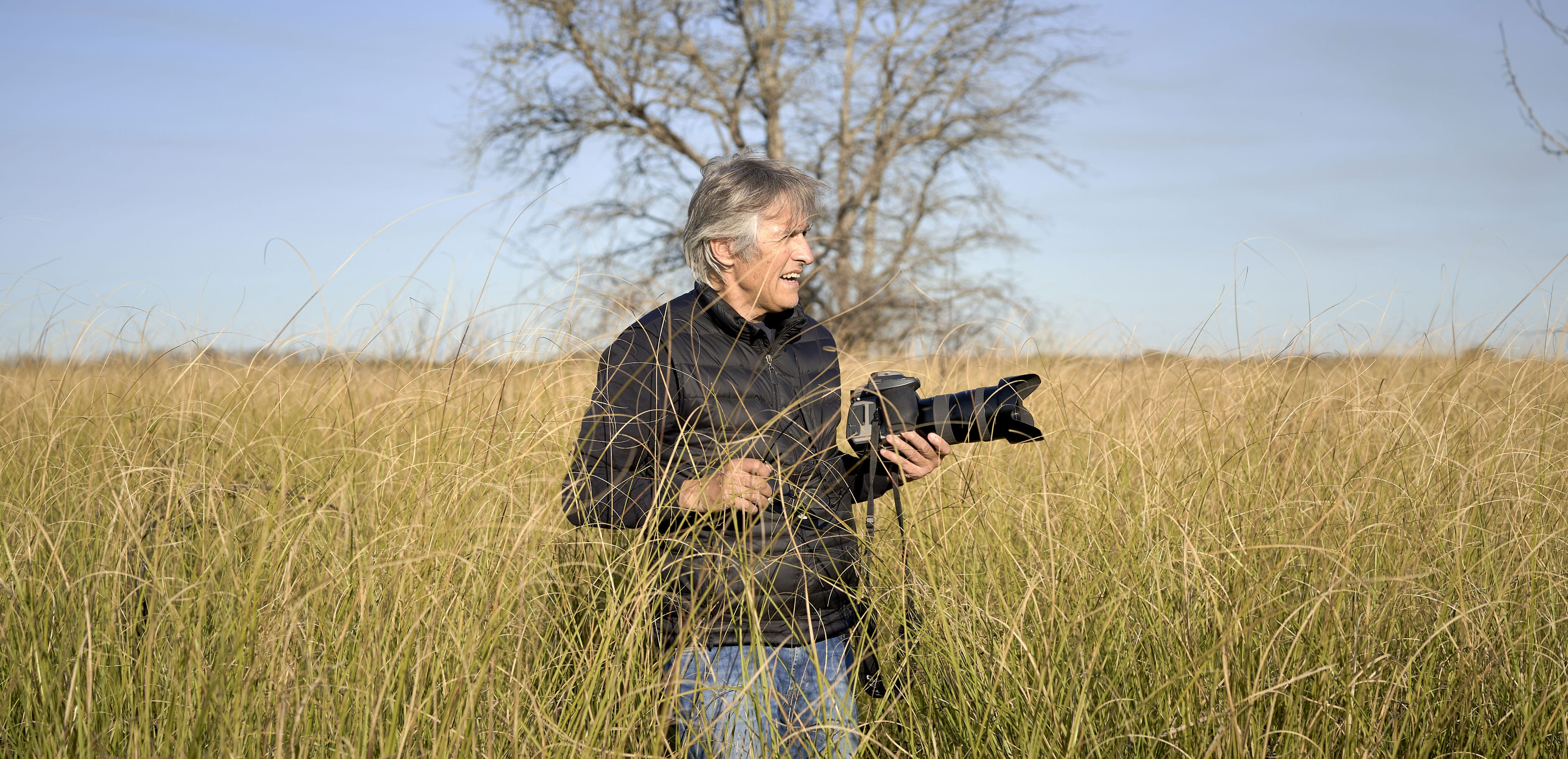 A retiree stands in a grassy field with a camera, illustrating how retirement side hustles can foster creativity, purpose and meaningful connection while providing extra income.