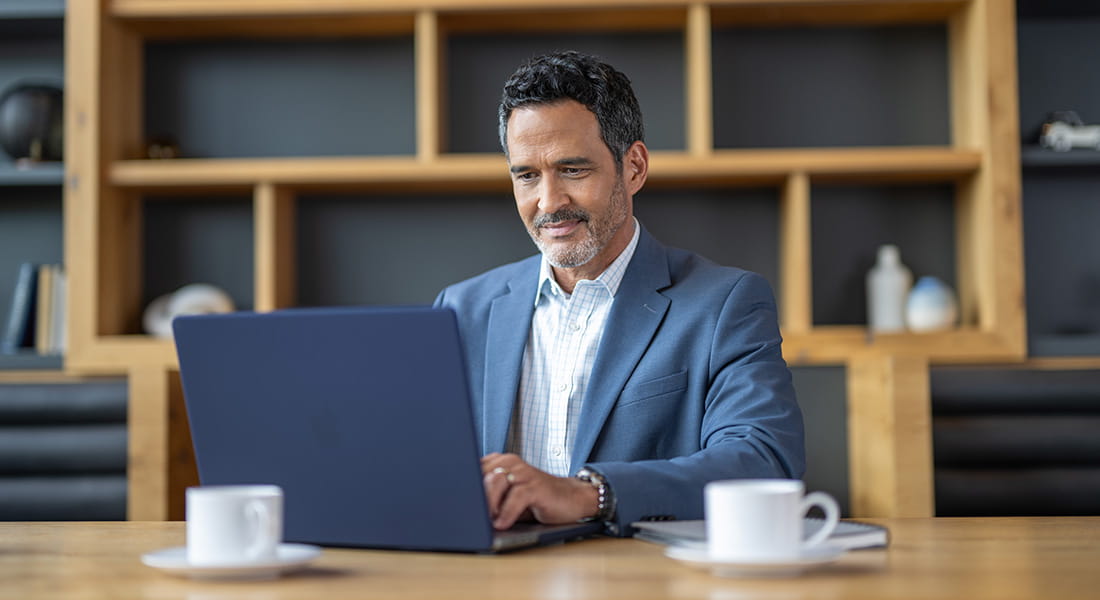 Male financial advisor using laptop with coffee
