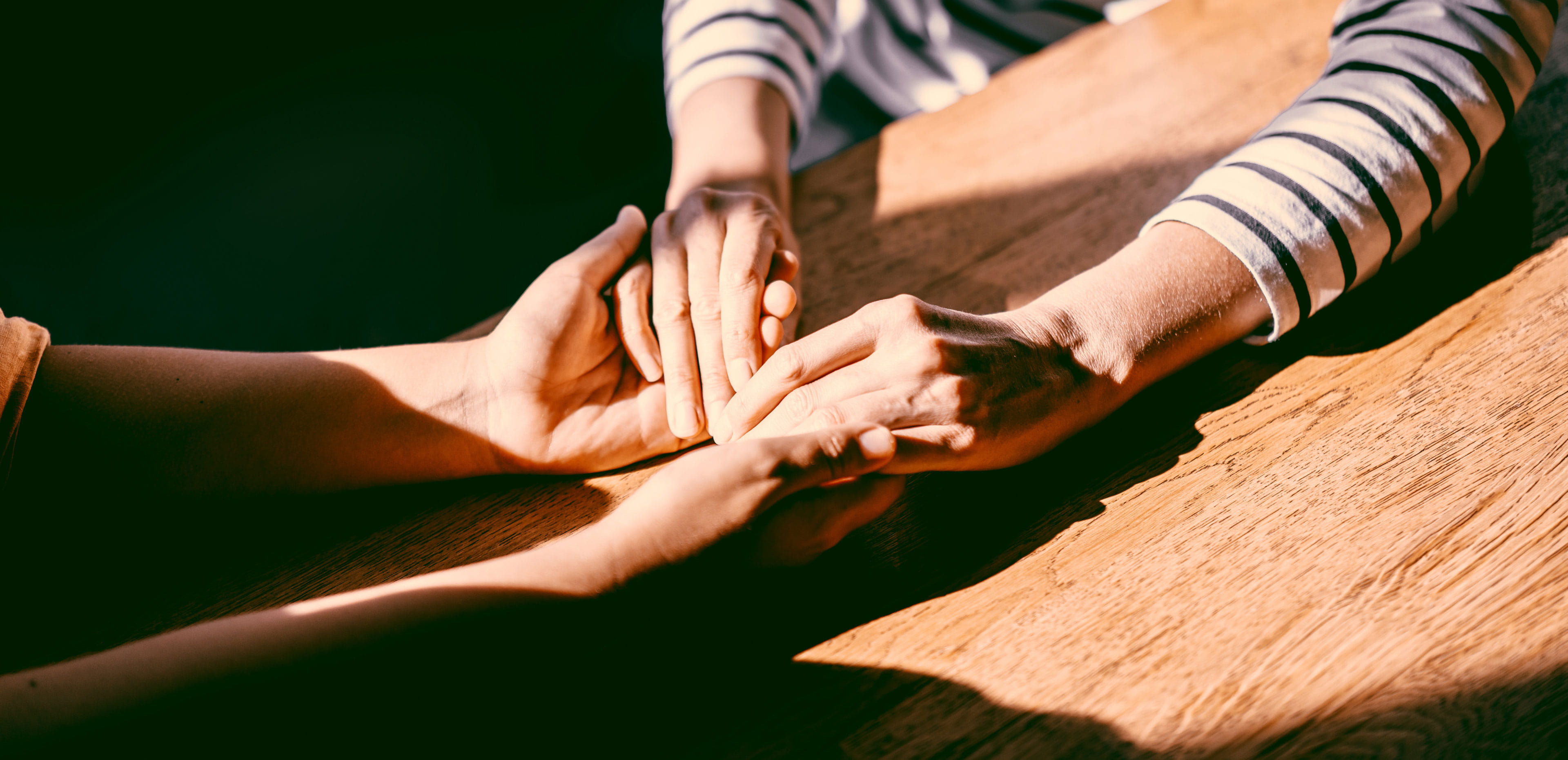 Two people hold hands across a table, symbolizing how estate planning can strengthen family connections, build generational wealth, and reflect personal values and legacy.