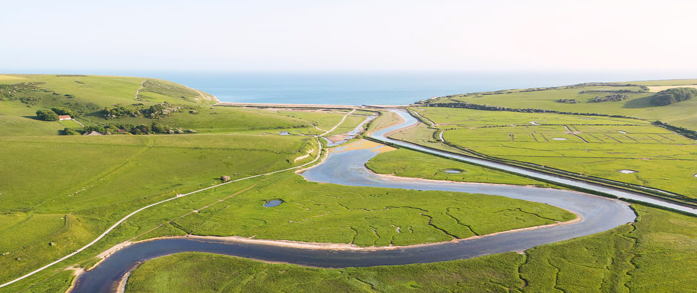 A winding river through open farmland, illustrating how overly specific charitable giving parameters can narrow a philanthropic mission.